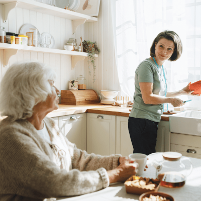 Pflegerin hilft alter Frau beim Kochen